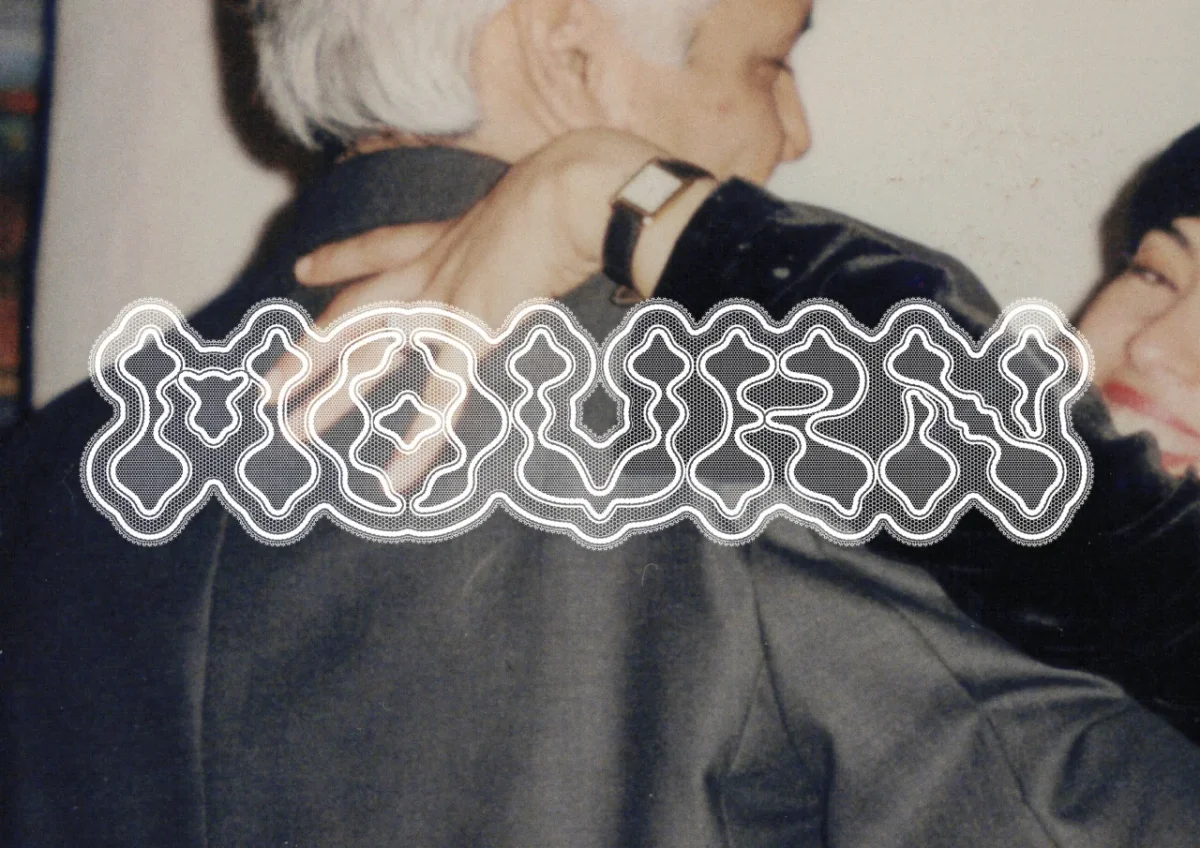 Ornate white geometric typeface design with interlocking symmetrical patterns overlaid on a photograph of a person wearing dark clothing