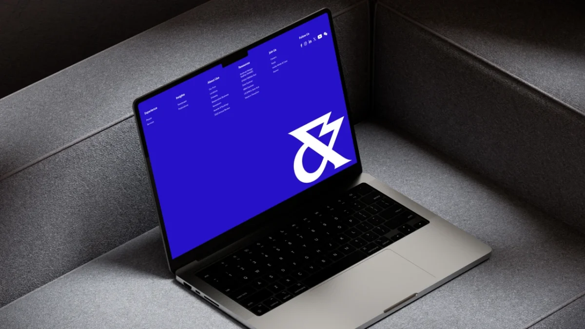 White & Case's new branding displayed on a laptop screen, featuring a white logo on electric blue background against a grey desk surface