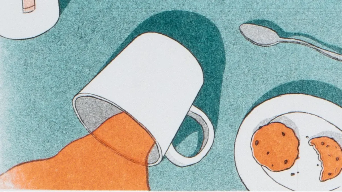 White mug tipped over spilling orange liquid beside a plate with two orange biscuits on a turquoise textured background, with a spoon nearby