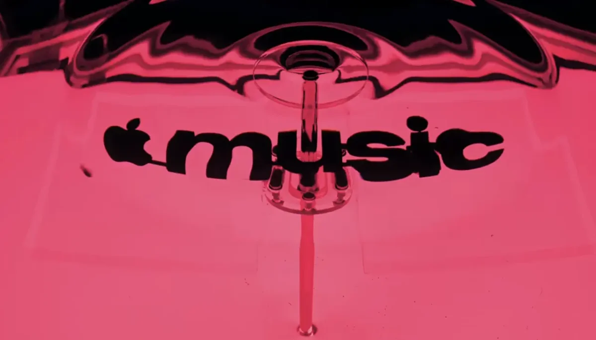 Apple Music logo in bright pink with a fluid, wave-like musical note design created from ripples in mineral oil