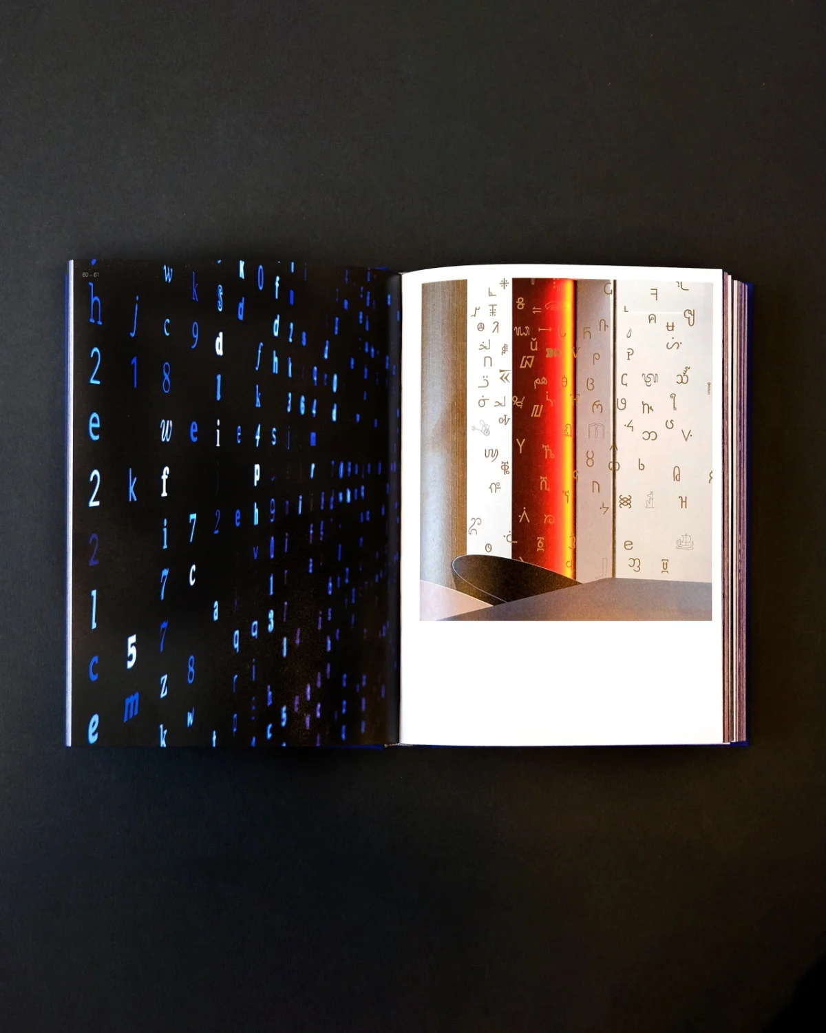 Open pages of SEA's 30th anniversary book showing blue pixelated text on the left and stacked colourful book spines on the right against a dark background
