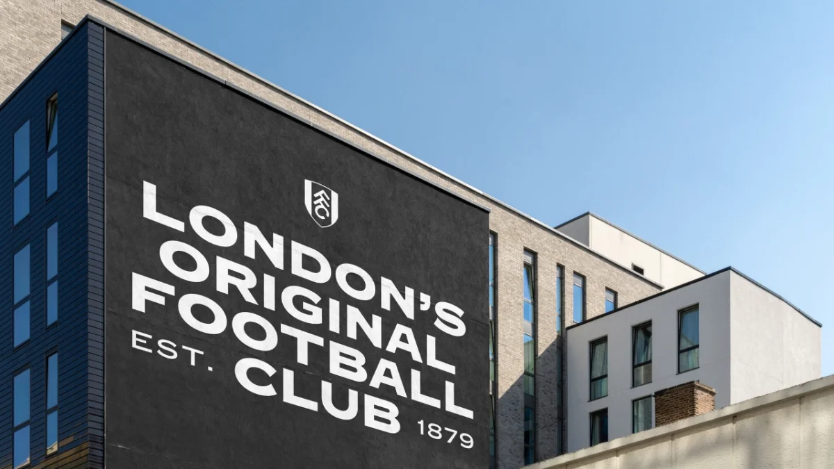 Large black wall mural on modern residential building displaying white text reading London's Original Football Club Est. 1879 with Fulham FC crest