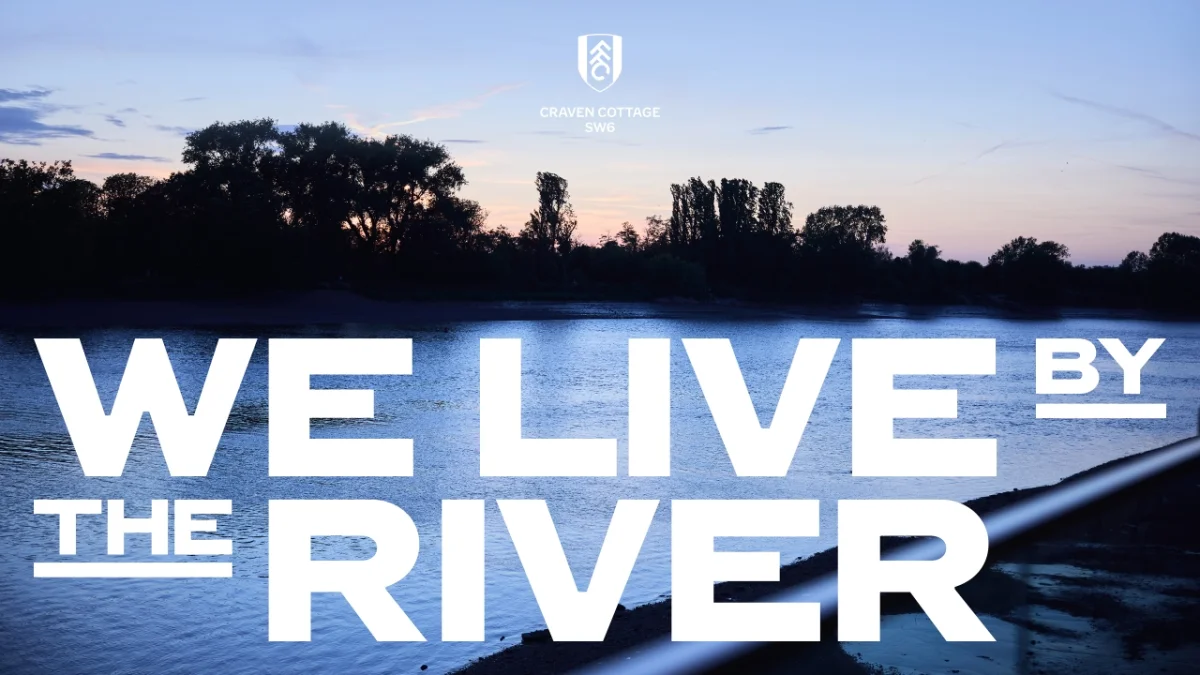 Twilight view of a river with silhouetted trees and a moored boat, overlaid with white text reading "We live by the river